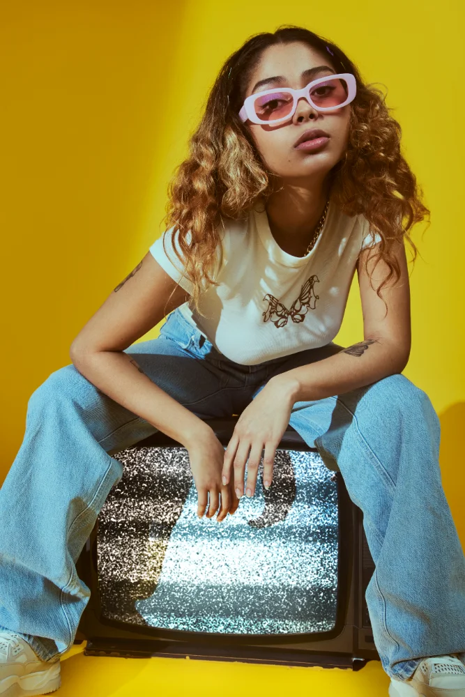 Jovem com estilo anos 2000 posando com TV